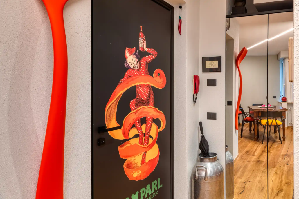 dettaglio dell'ingresso con porta nera decorata con grafica campari e appendiabiti di design a forma di cucchiaio rosso