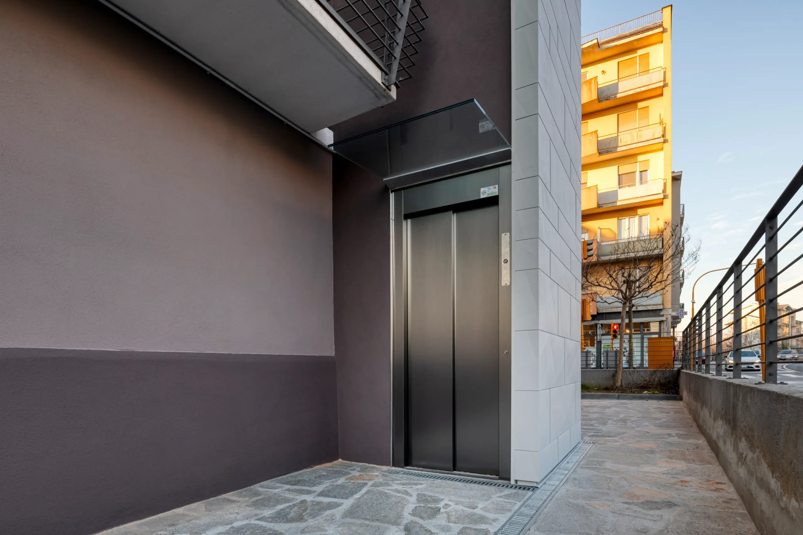 ascensore esterno realizzato su edificio residenziale con struttura verticale rivestita in pannelli chiari