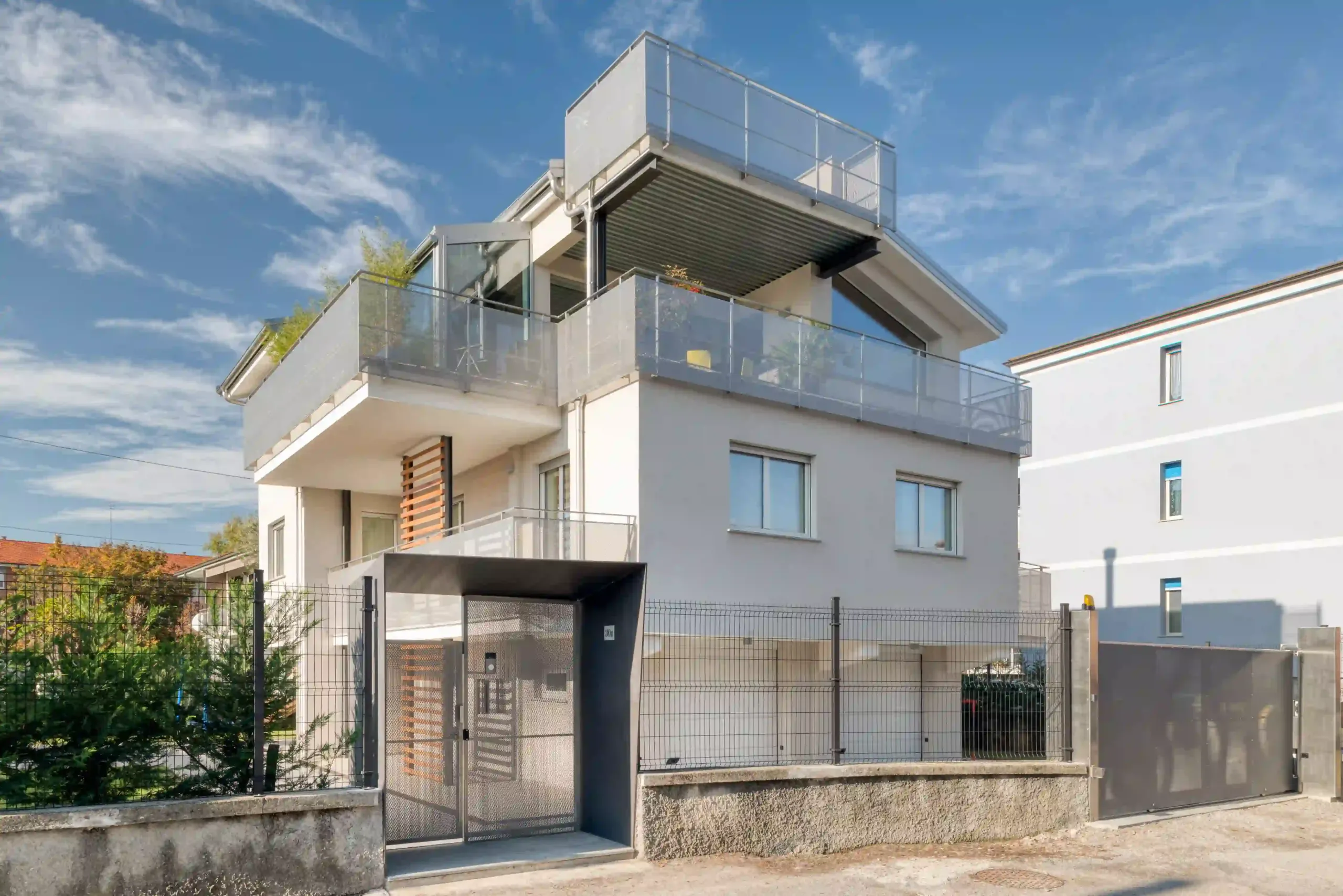 villa moderna con terrazze su più livelli, parapetti in metallo e volumi sovrapposti