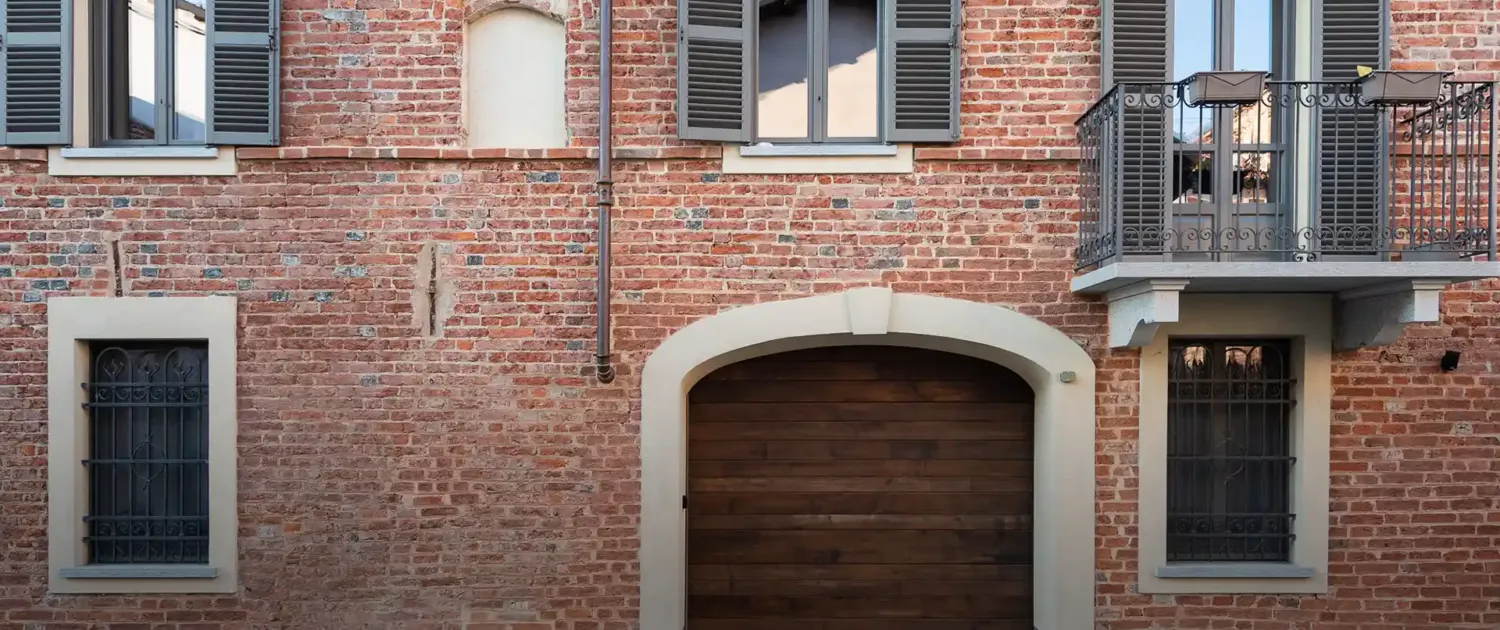 edificio storico in mattoni a vista con grande portone in legno e balconi con ringhiere in ferro
