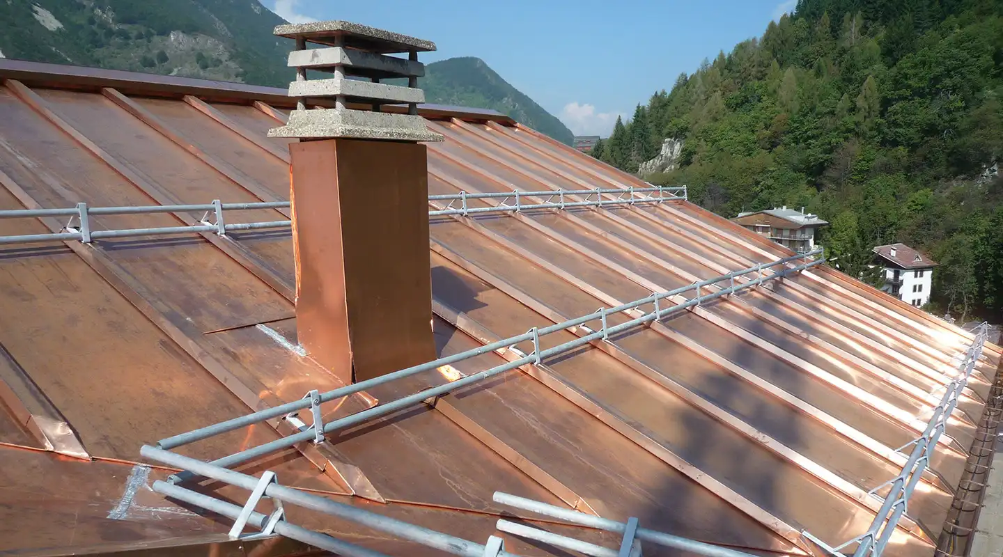 dettaglio tecnico della copertura in rame e sistema di paraneve metallico a doppio tubo installato sulla falda
