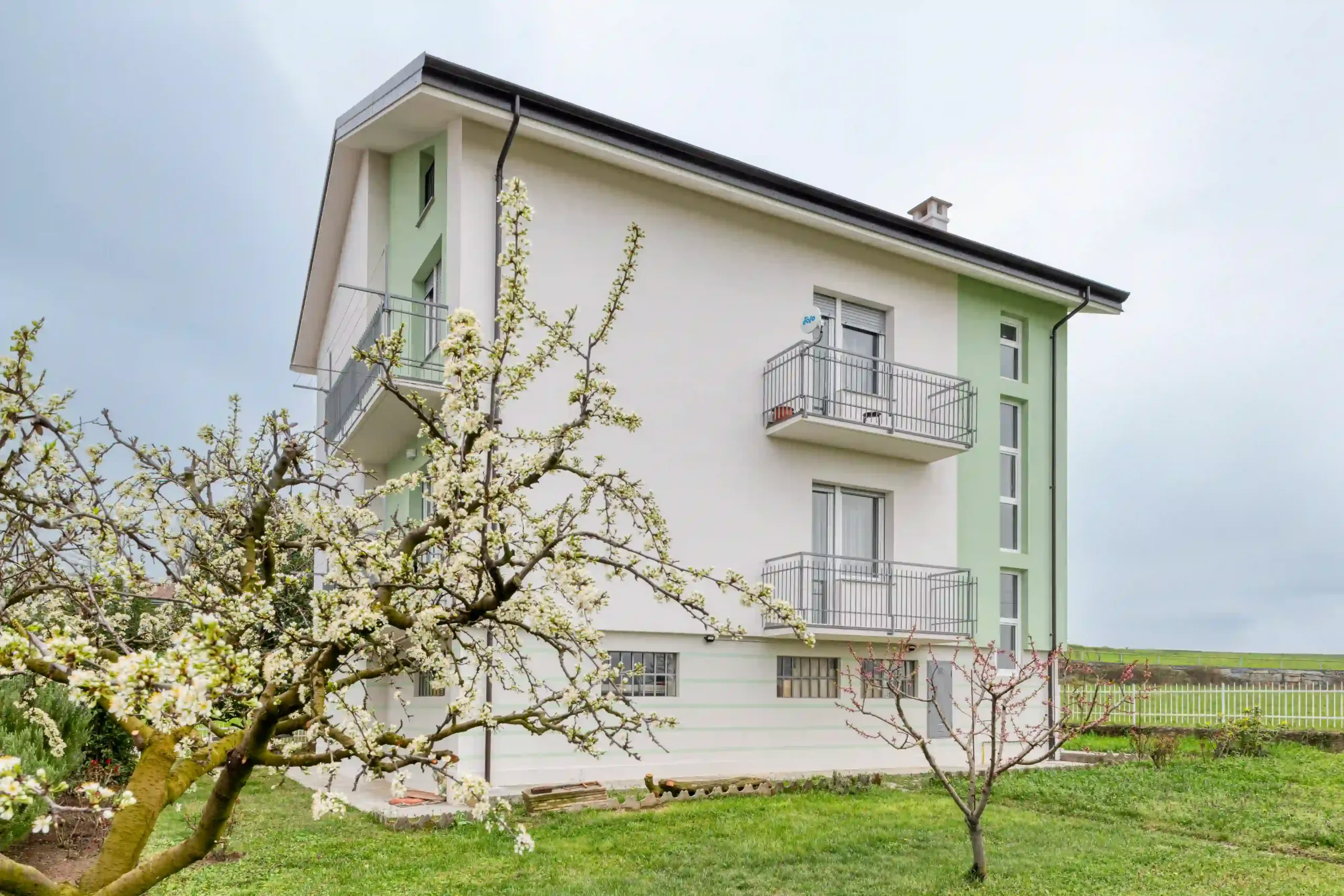 prospetto laterale dell'edificio residenziale immerso nel verde con alberi e finiture esterne pulite