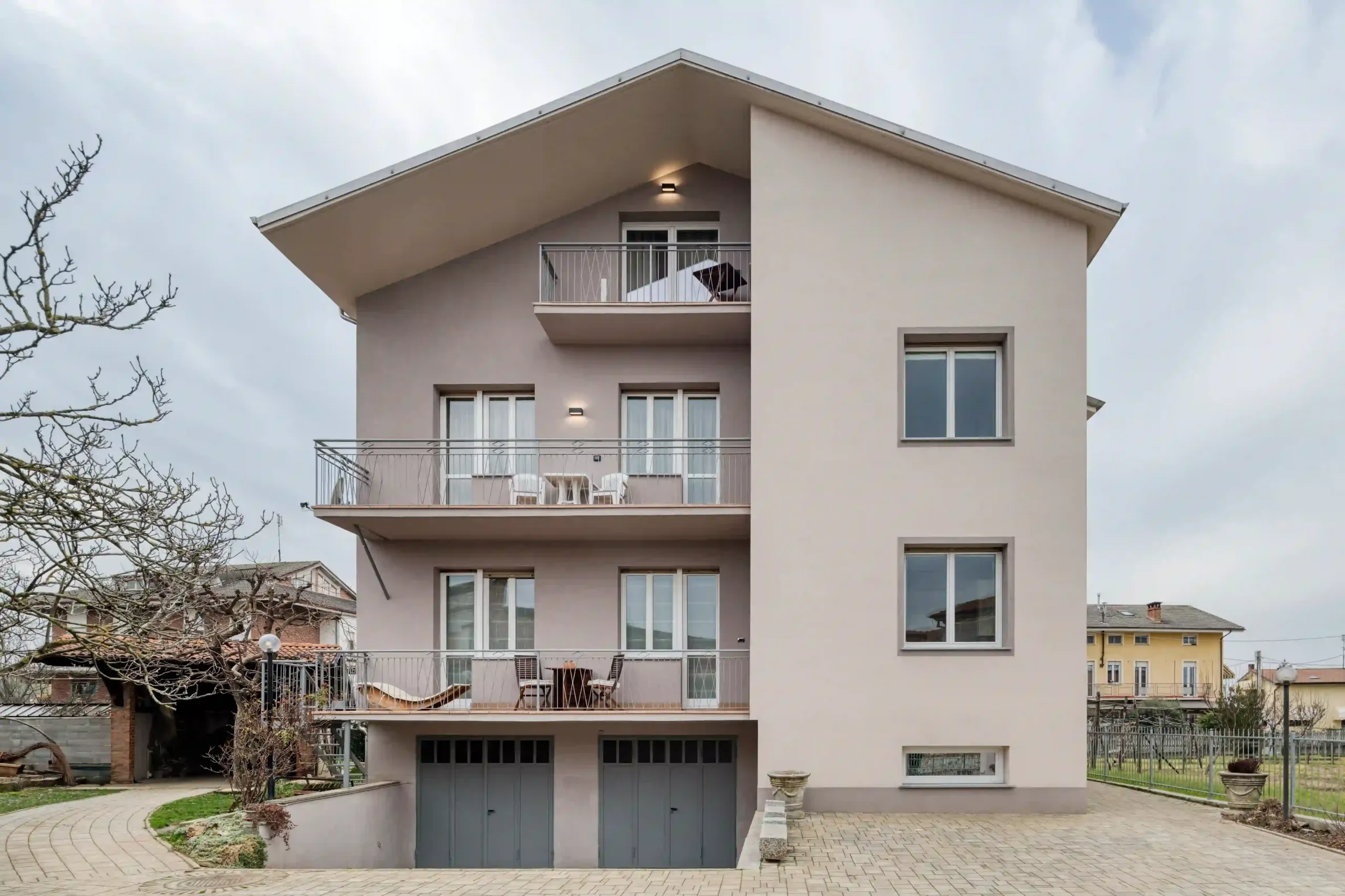 prospetto principale dell'edificio residenziale con intonaco bicolore, ampie finestre e ingressi ai garage al piano terra