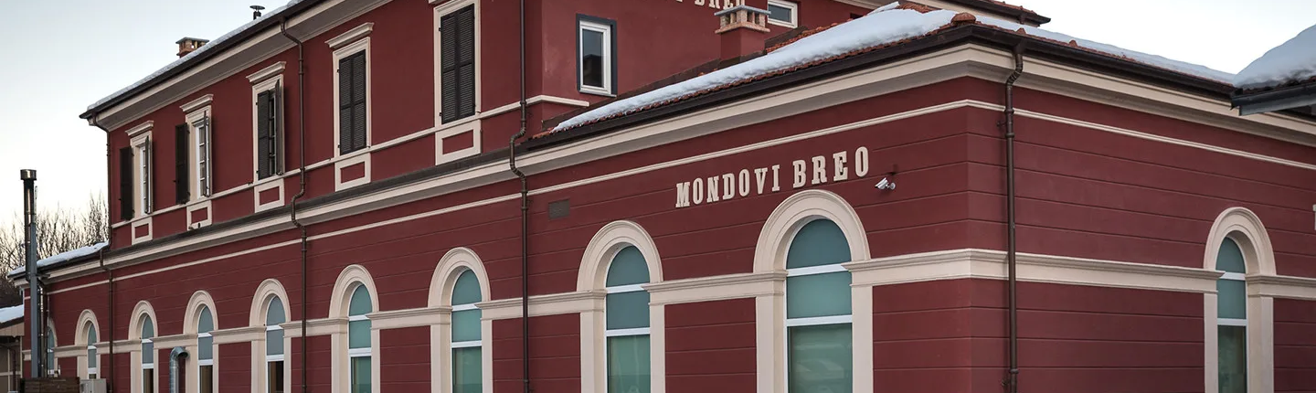 edificio ferroviario restaurato con archi e scritta mondovì breo sulla facciata