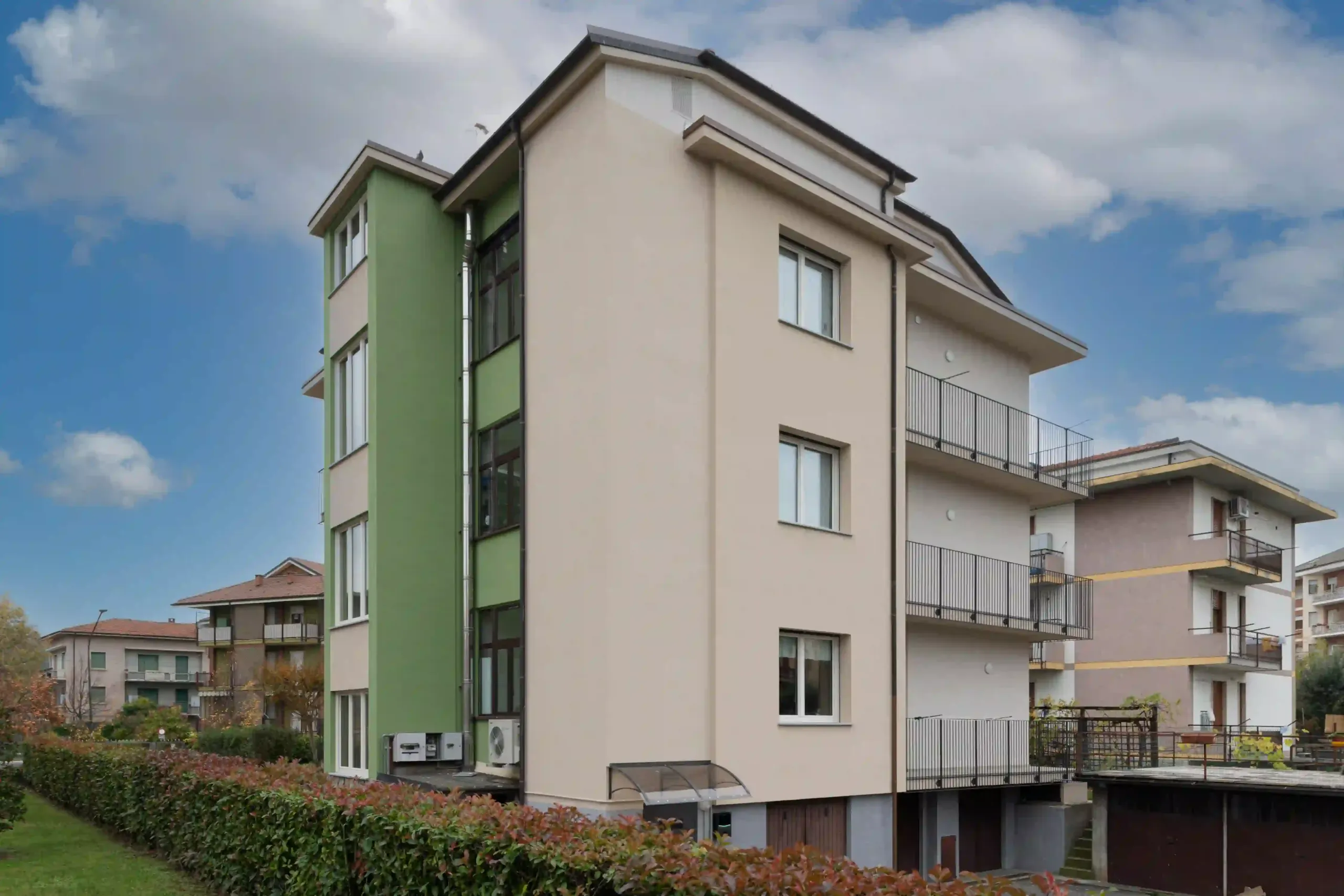 prospetto laterale dell'edificio residenziale con finiture color crema e verde mela e dettagli tecnici a vista
