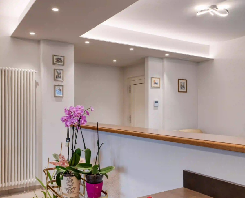 interno moderno con controsoffitto illuminato, faretti incassati e zona living luminosa