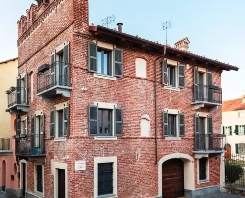 palazzo medievale in mattoni caratterizzato da balconi in ferro e merlatura decorativa sul tetto