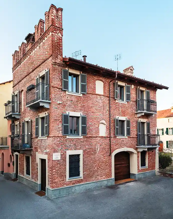palazzo medievale in mattoni caratterizzato da balconi in ferro e merlatura decorativa sul tetto
