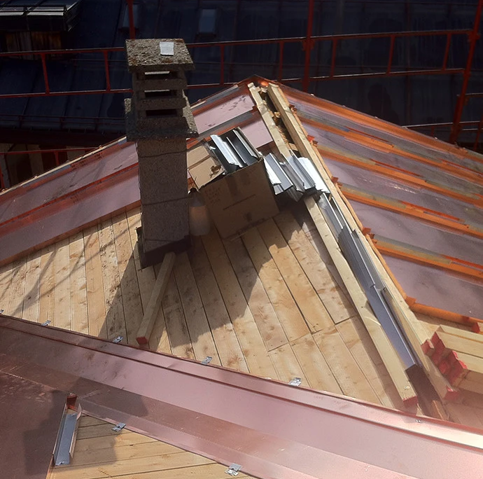 fase di lavorazione del tetto con installazione di lastre in rame su struttura in legno e teli protettivi di cantiere