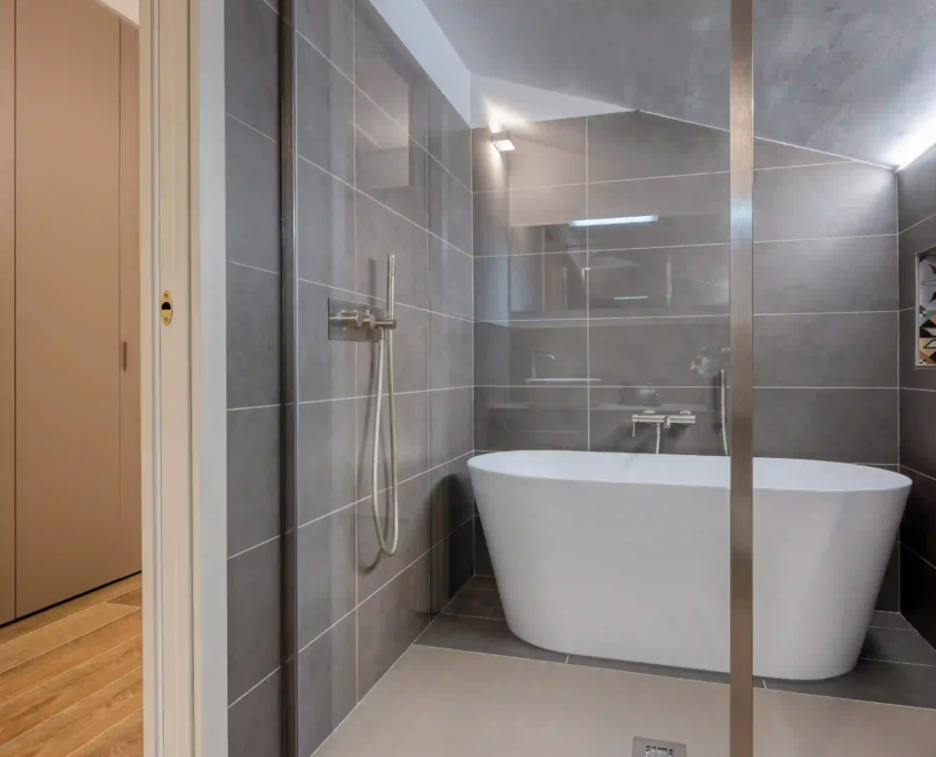 bagno moderno con doccia walk-in e vasca freestanding sotto copertura inclinata