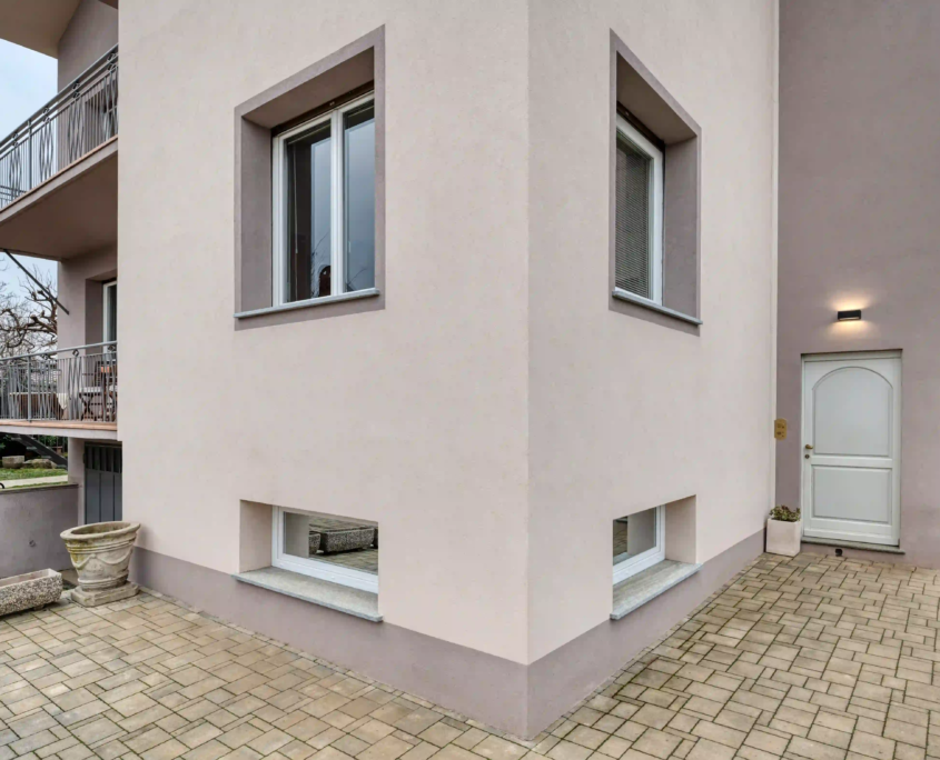 dettaglio dell'angolo dell'edificio con finiture di pregio, finestre moderne e porta d'ingresso bianca coordinata