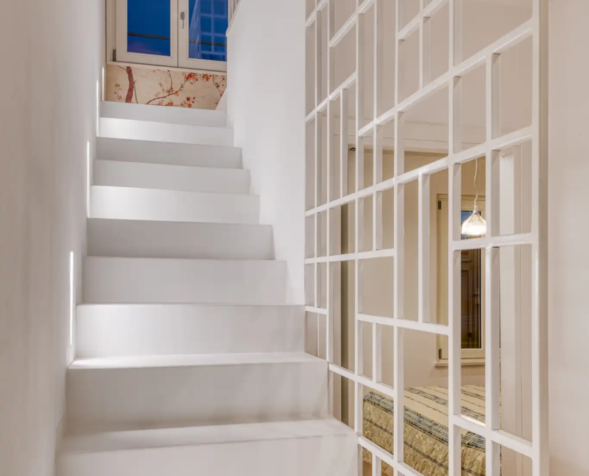 scala interna bianca con parapetto a griglia geometrica e sfondo con carta da parati botanica