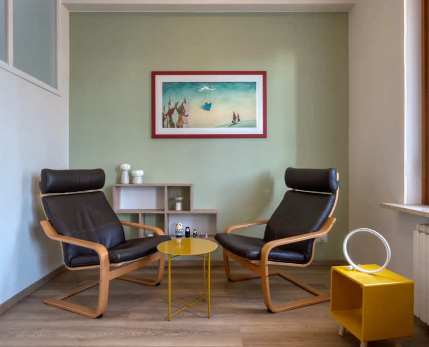 zona giorno con tavolino rotondo giallo, poltrone ergonomiche e nicchie a muro con piccole decorazioni