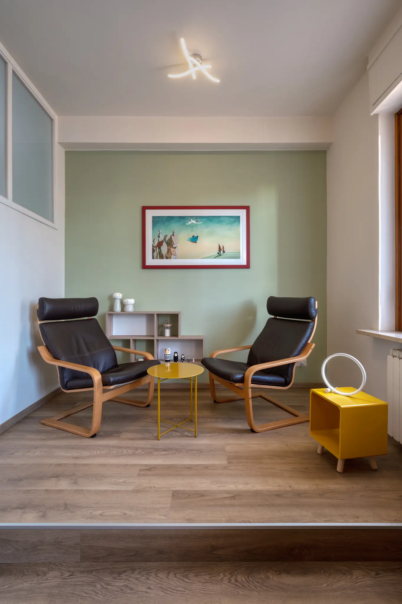 zona giorno con tavolino rotondo giallo, poltrone ergonomiche e nicchie a muro con piccole decorazioni