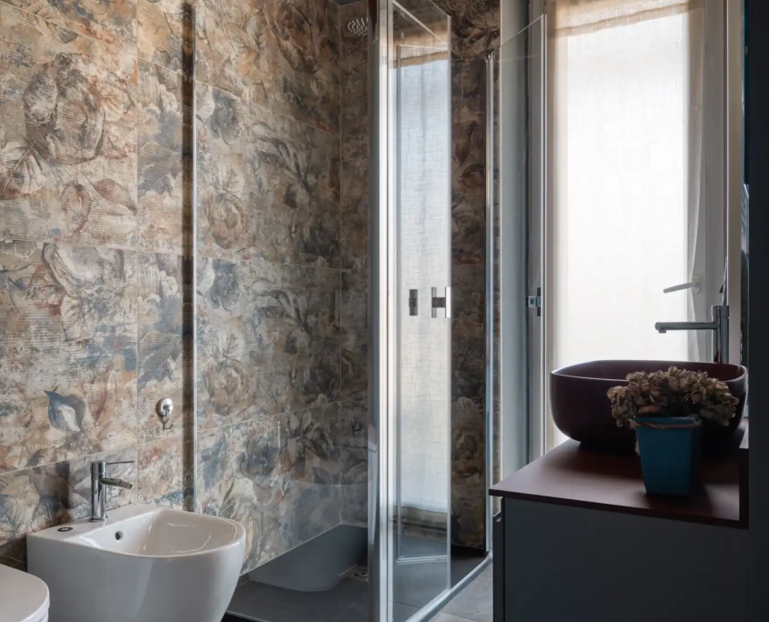 bagno moderno con rivestimenti decorativi, doccia in vetro e lavabo contemporaneo