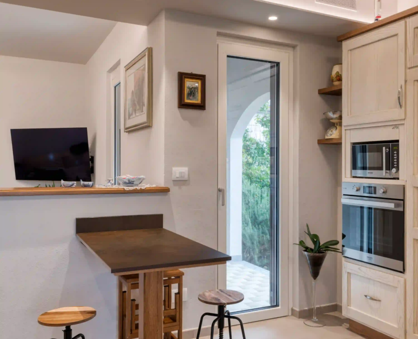 angolo cucina con penisola, sgabelli e accesso diretto al giardino