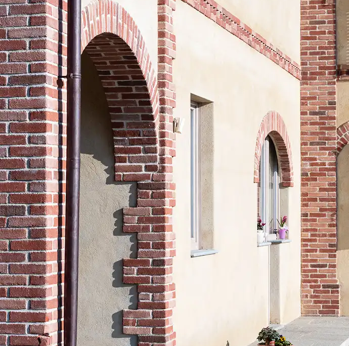 particolare architettonico di pilastro e arco in mattoni a vista e piccoli vasi di fiori decorativi