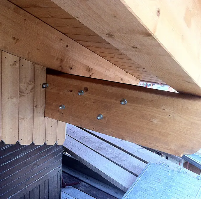carpenteria in legno del sottotetto con focus sulla giunzione della trave portante e perlinato in legno chiaro