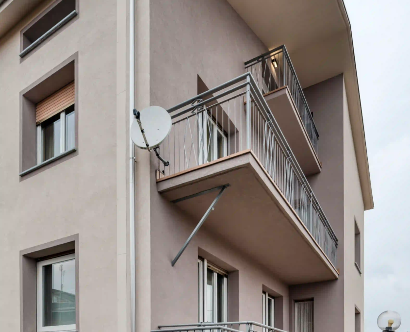 vista laterale della facciata con balconi aggettanti, scala esterna di sicurezza in metallo e antenna parabolica installata