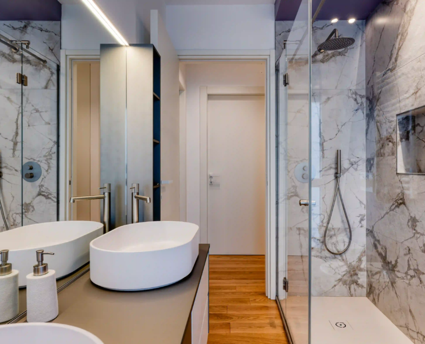 interno bagno moderno con pareti effetto marmo, lavabo bianco e box doccia in vetro