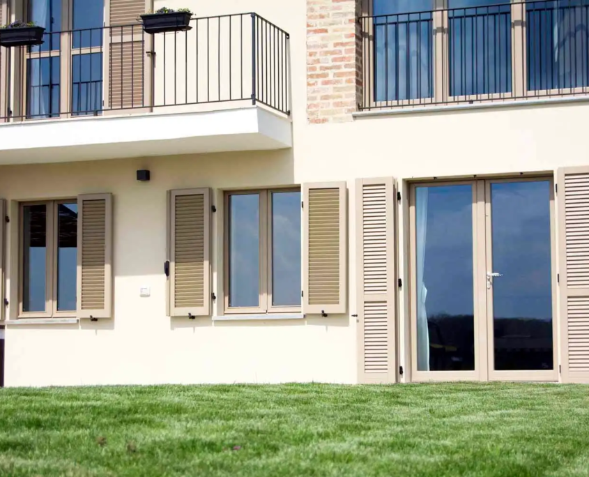 dettaglio di finestre con persiane beige e balcone in ferro battuto