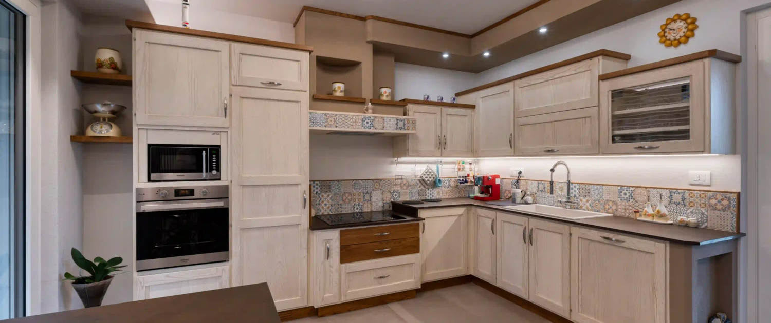 cucina in stile classico con mobili chiari, piano di lavoro scuro e rivestimento decorativo