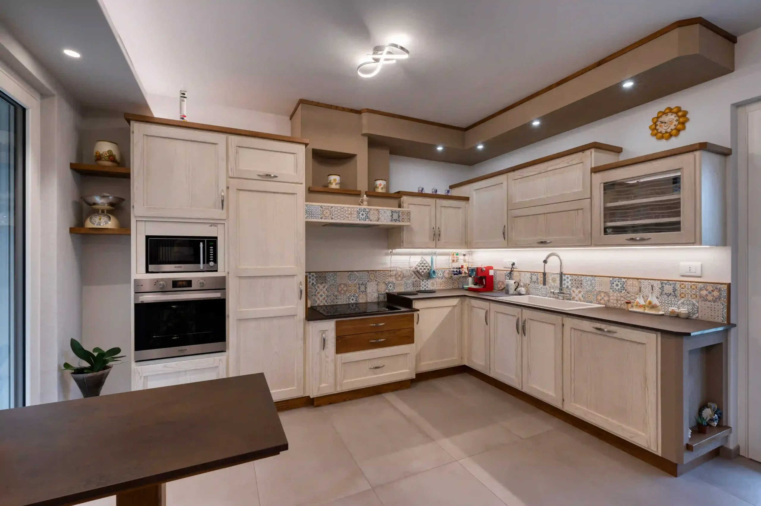 cucina in stile classico con mobili chiari, piano di lavoro scuro e rivestimento decorativo