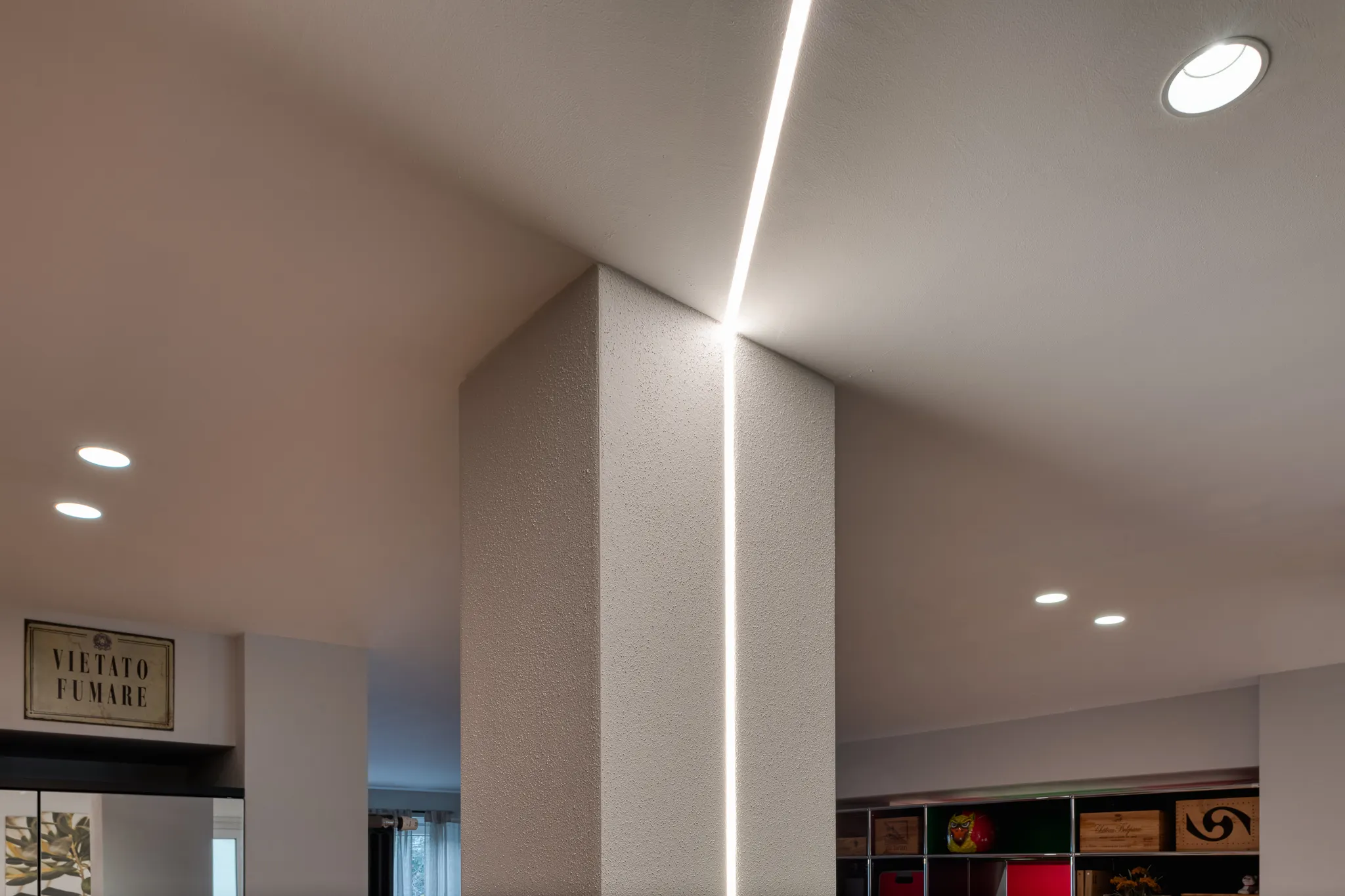 dettaglio illuminotecnico di pilastro con lama di luce led verticale incassata tra parete e soffitto