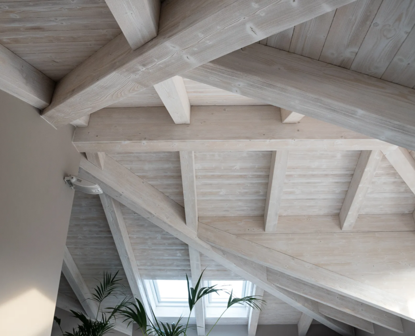 05_immagine_progetto_cielo_recuperato dettaglio della struttura del tetto con travi in legno, ferramenta di montaggio e luce naturale dall'alto