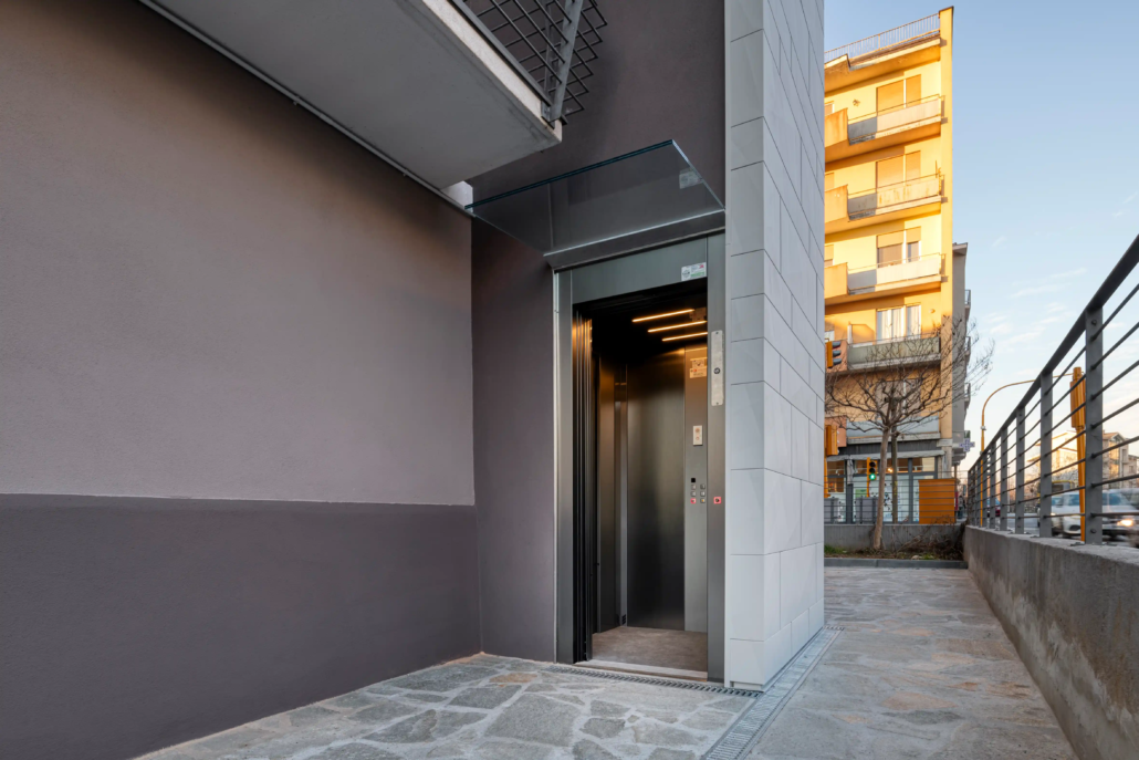 ingresso ascensore esterno con porta aperta inserito in struttura architettonica contemporanea
