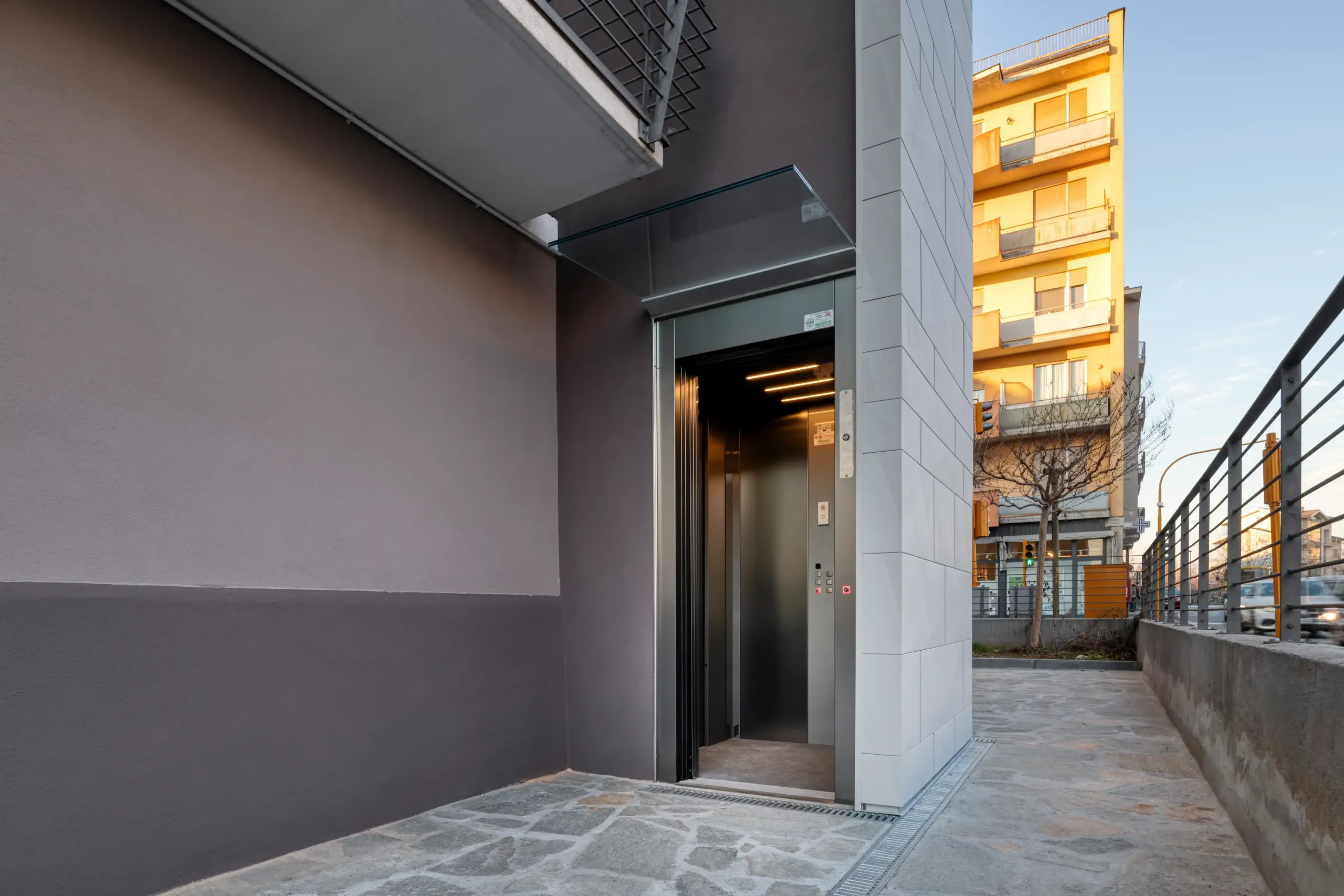05_immagine_progetto_doga_vertigo ingresso ascensore esterno con porta aperta inserito in struttura architettonica contemporanea