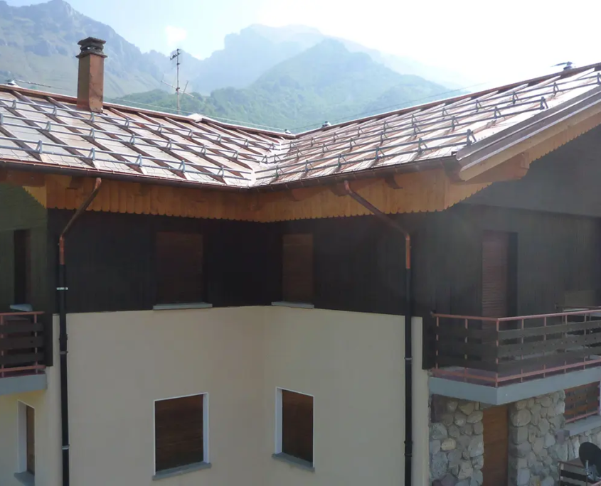 facciata con pluviali in rame a vista, balconi con ringhiere in legno e basamento con inserti in pietra naturale