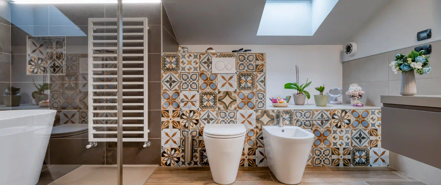 bagno mansardato con rivestimenti decorativi, lucernario e sanitari moderni