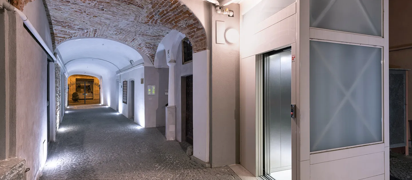 corridoio d'ingresso con soffitto a volta illuminato, pavimentazione in pietra e accesso all'ascensore