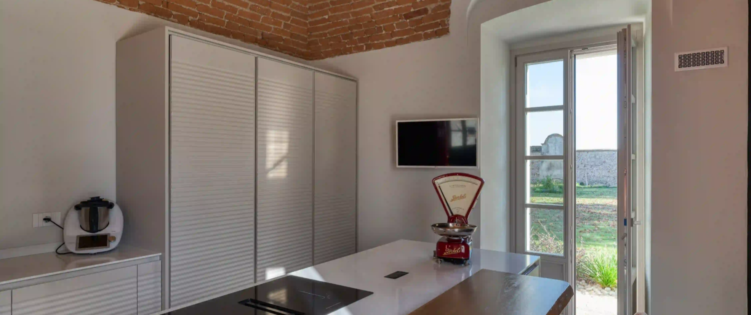 interno cucina moderna con isola bianca e bancone in legno massiccio sotto un soffitto a volta in mattoni rossi a vista