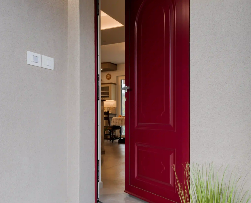 porta d’ingresso rossa aperta su interno luminoso con dettagli moderni