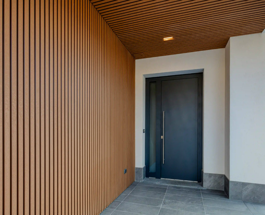 06_immagine_progetto_casa_fascione Ingresso moderno con porta scura e rivestimento in doghe di legno verticale