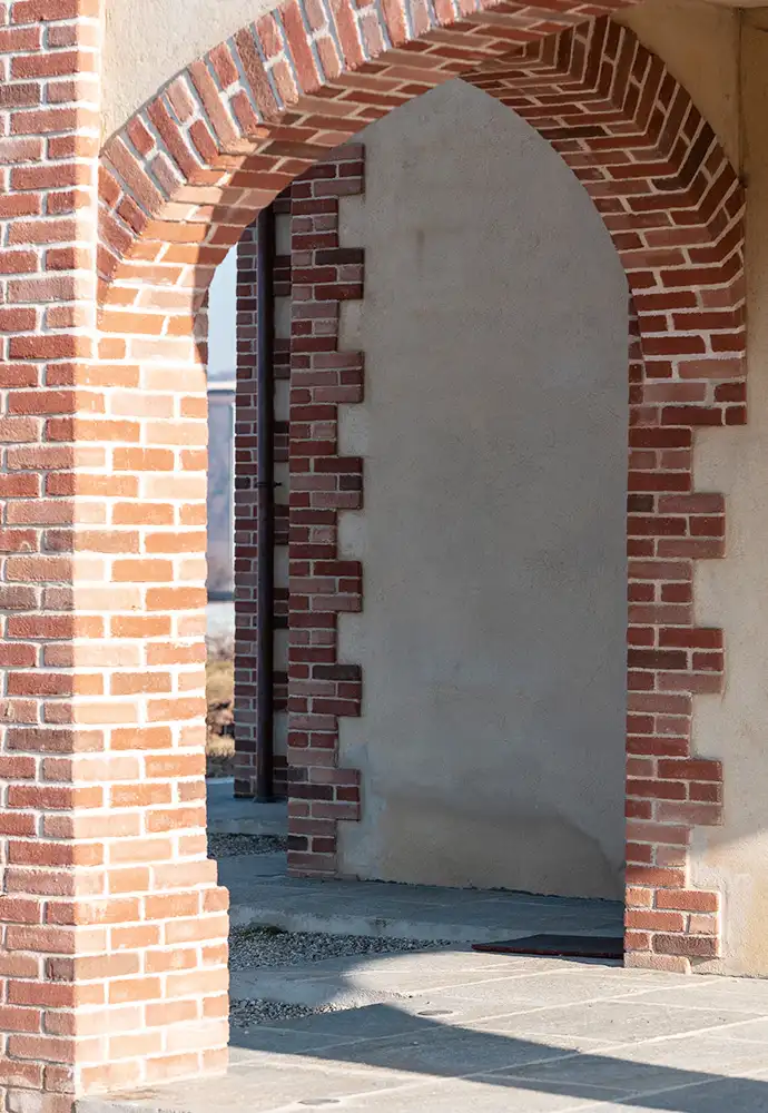 scorcio prospettico del porticato esterno con successione di archi in mattoni e finiture murali effetto rustico