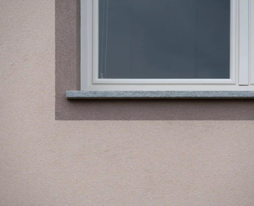 dettaglio architettonico di finestra con davanzale in pietra e cornice scura che sottolinea i volumi della facciata