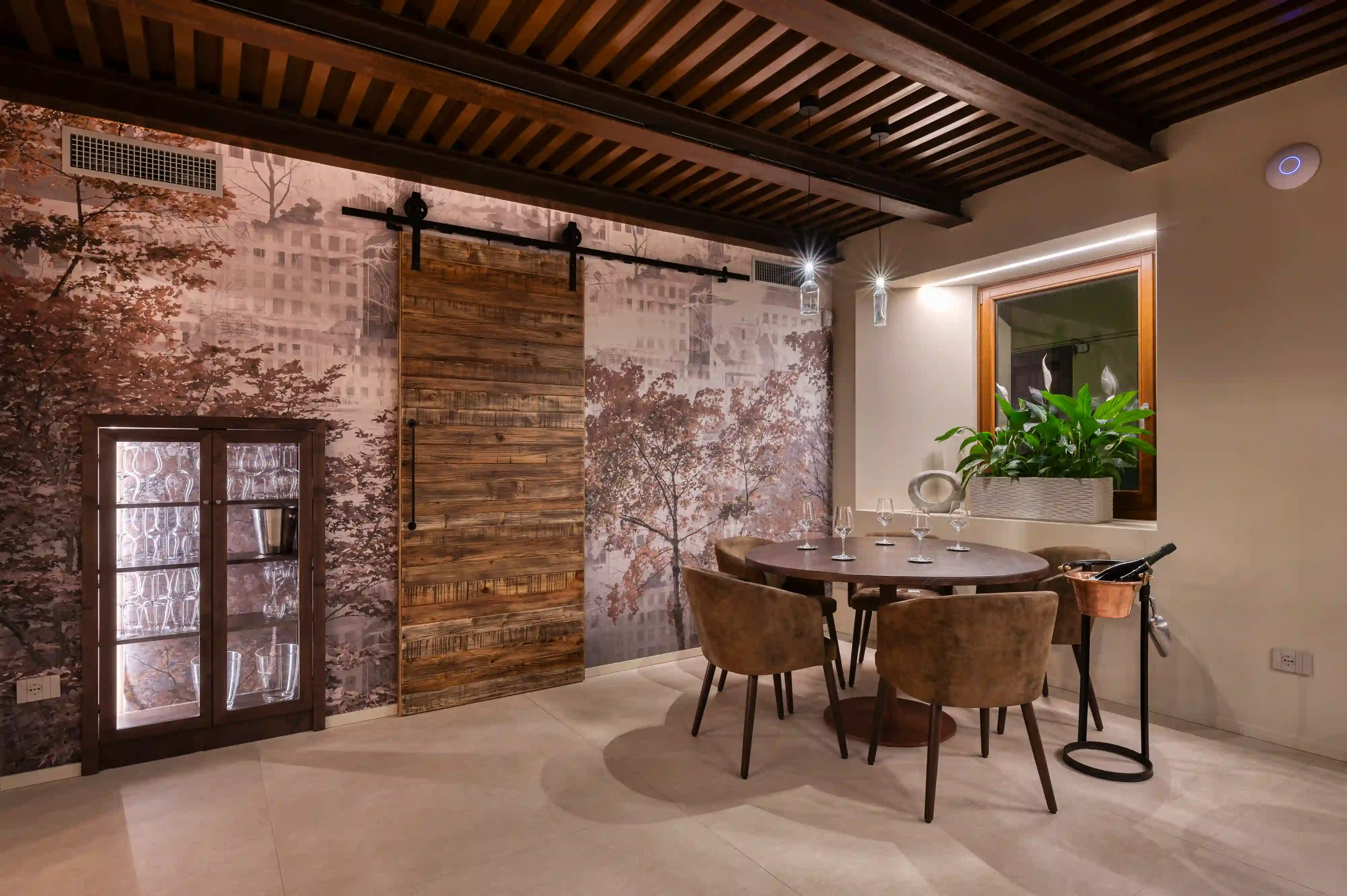 area dining con parete decorata da carta da parati con alberi, porta scorrevole in legno di recupero e soffitto tecnico scuro