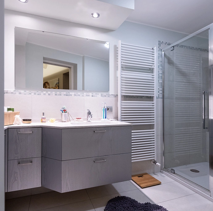 bagno moderno con mobile lavabo sospeso grigio, grande specchio rettangolare, termoarredo bianco e box doccia