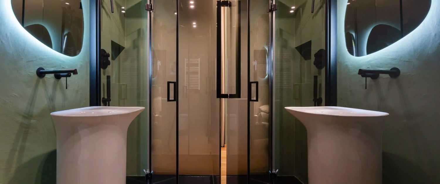dettaglio zona lavabo con lavandino a colonna, pareti color verde bosco e specchio con luce led integrata