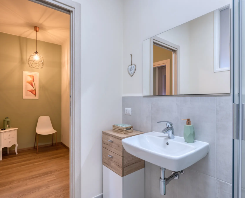 zona lavabo funzionale con lavandino bianco, mobiletto in legno e specchio