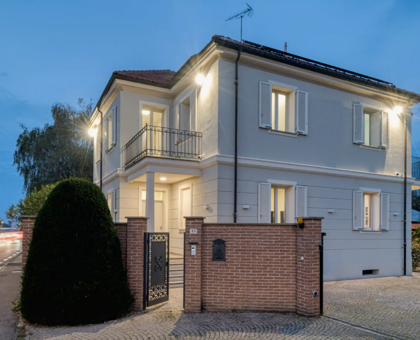 Villa in stile tradizionale con facciata chiara, balcone in ferro battuto e illuminazione serale