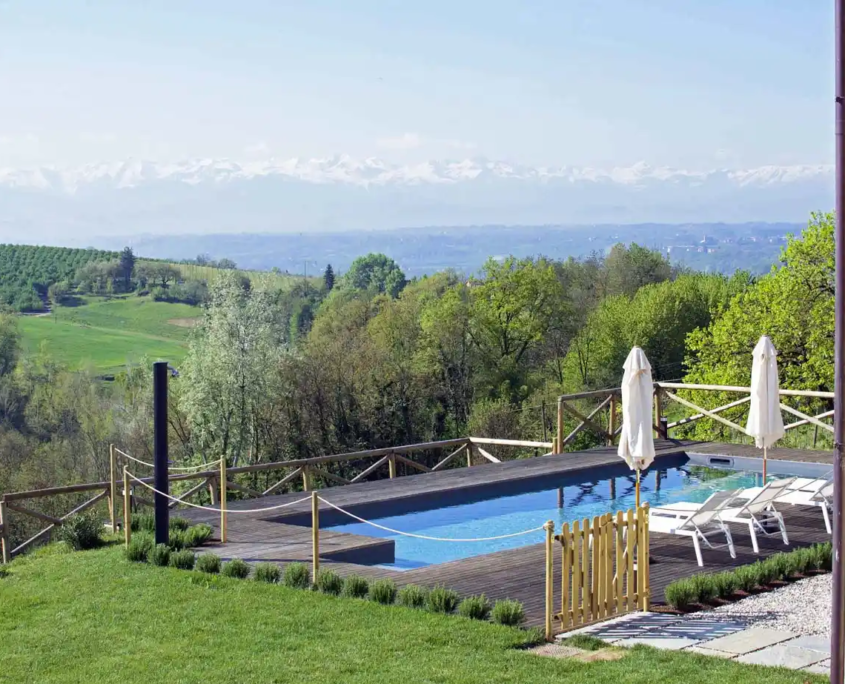 piscina immersa nel verde con vista su vigneti e montagne all’orizzonte