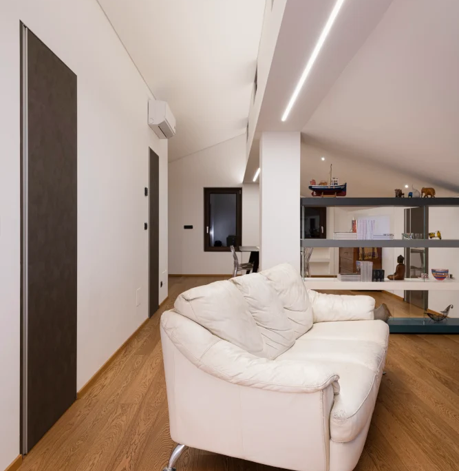 sottotetto con pavimentazione in parquet, porte filomuro scure e led sul soffitto