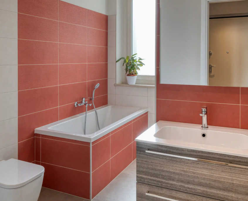 07_immagine_progetto_stella_alpina bagno contemporaneo con vasca, rivestimento murale color ruggine e mobile lavabo con ampi cassettoni in legno