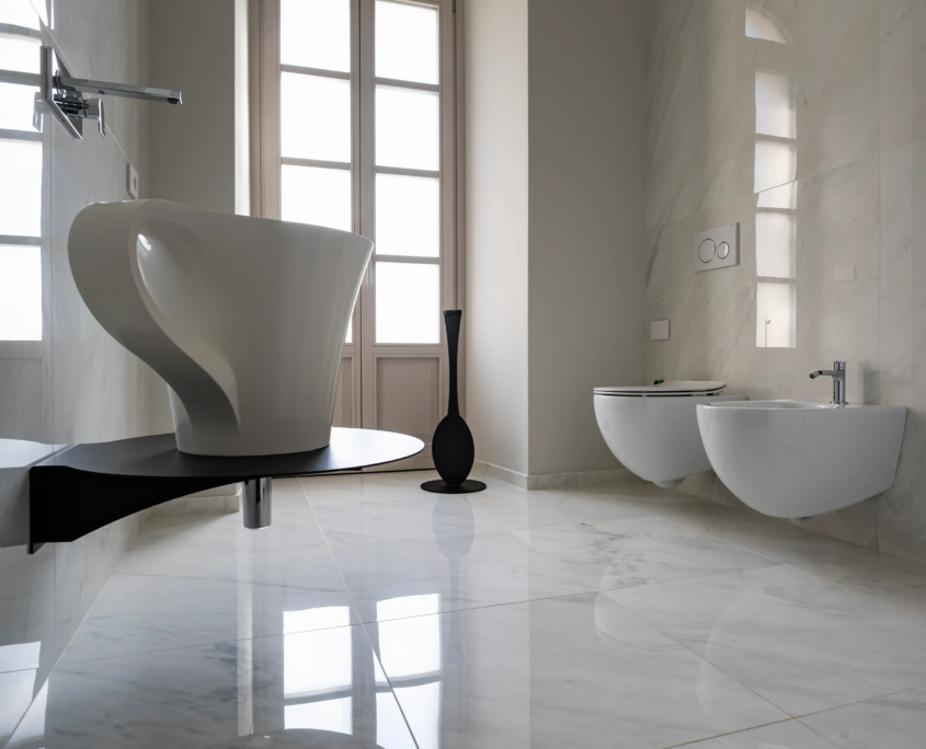 bagno padronale lussuoso con rivestimento in marmo bianco calacatta, grande finestra ad arco e lavabo di design scultoreo