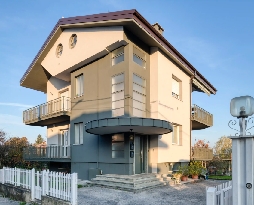 vista esterna di casa moderna con facciata bicolore, tetto a falde e balconi con ringhiere metalliche