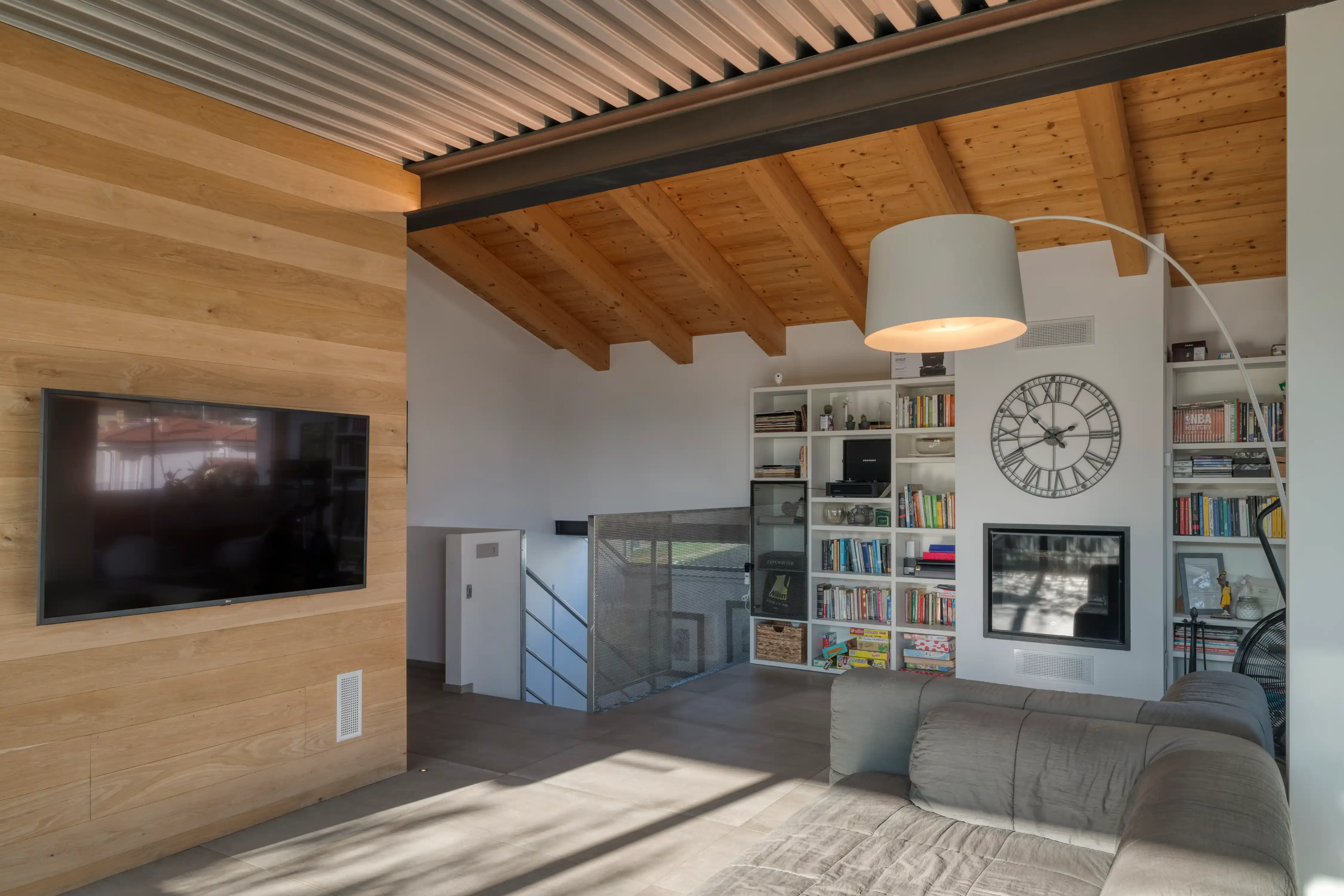 zona living con soffitto in legno, camino integrato e arredi su misura